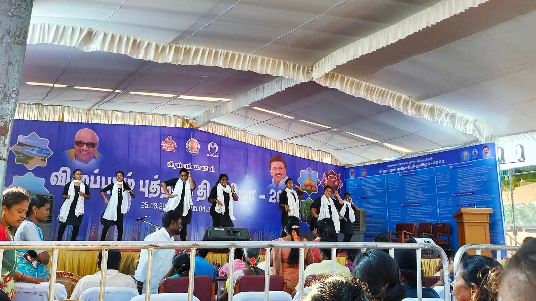 Students perform on the book-fair stage under a blue banner.